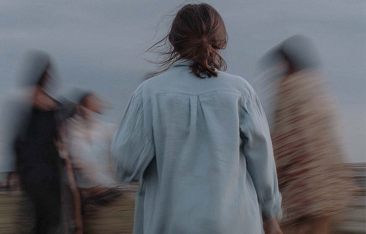 A person standing amidst blurred, chaotic motion, symbolizing the different inner voices and parts addressed in IFS therapy.